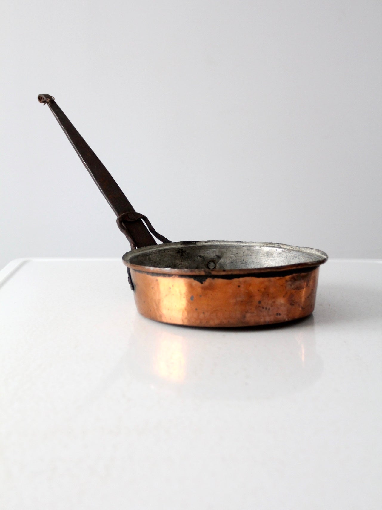 Antique French copper pan outlet with a long wrought iron handle for farmhouse display